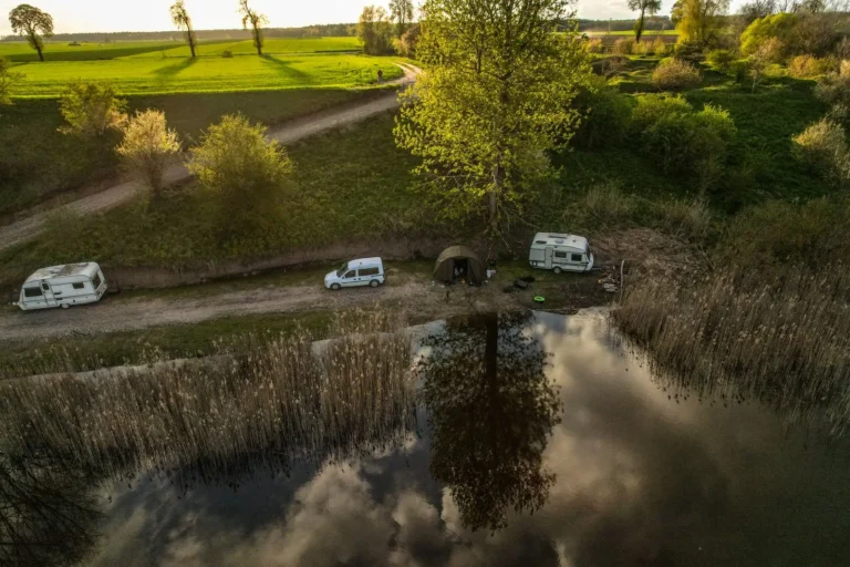 Vue aérienne d’un camping au bord d’un lac, avec ses caravanes