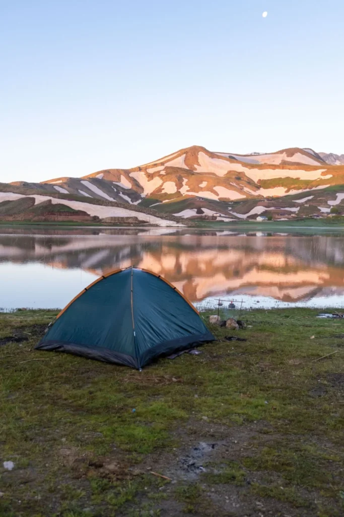 Camping au bord d’un lac de montagne au lever du jour
