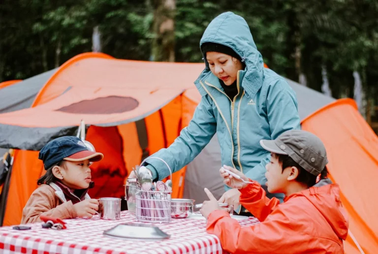 Une mère sert le repas à ses enfants devant des tentes orange