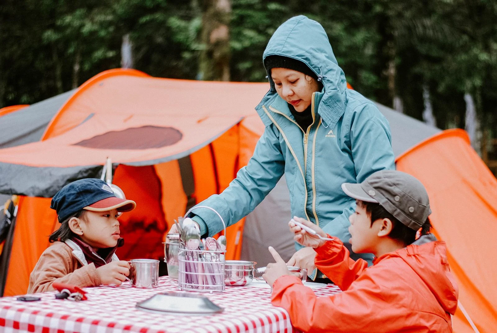 Une mère sert le repas à ses enfants devant des tentes orange